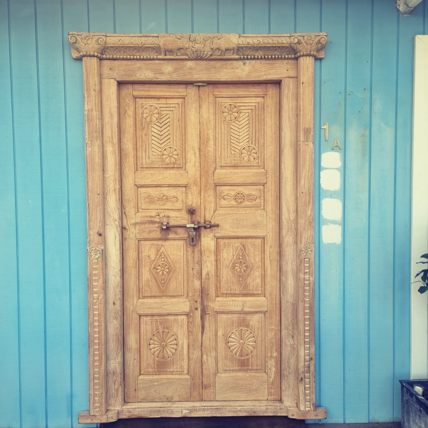 Ornate carved timber double door on blue timber wall