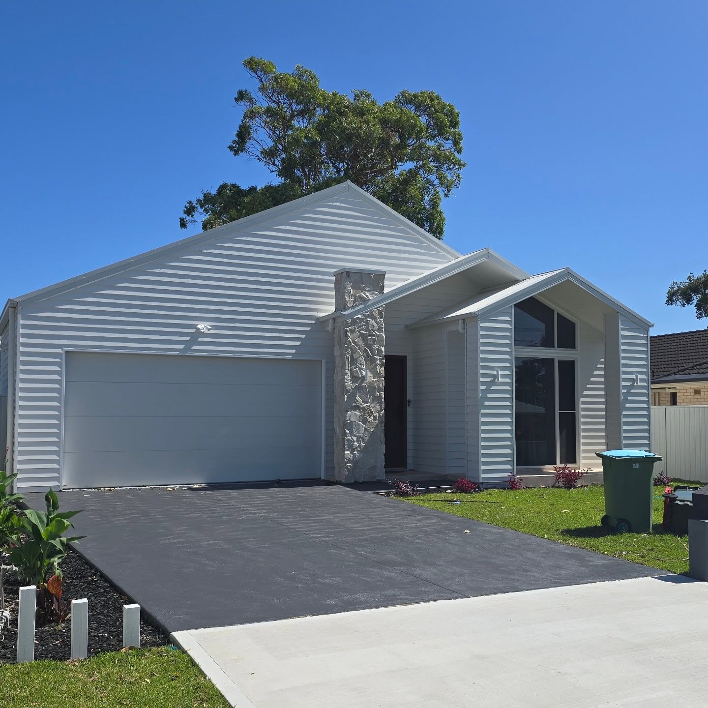 Completed weatherboard home with stone chimney and gable roof